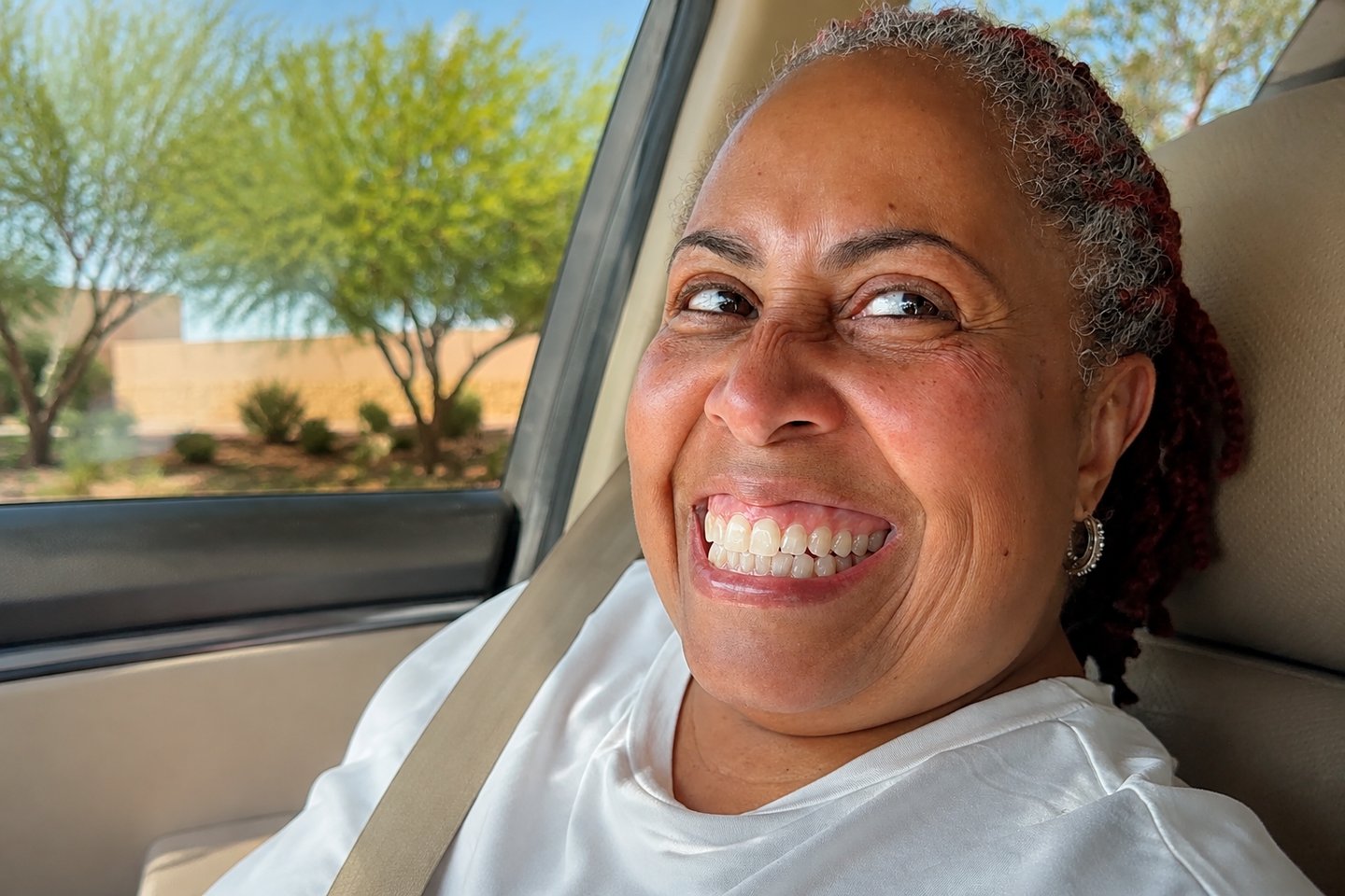 A woman beaming in the passenger seat as her song for a 50th birthday plays.